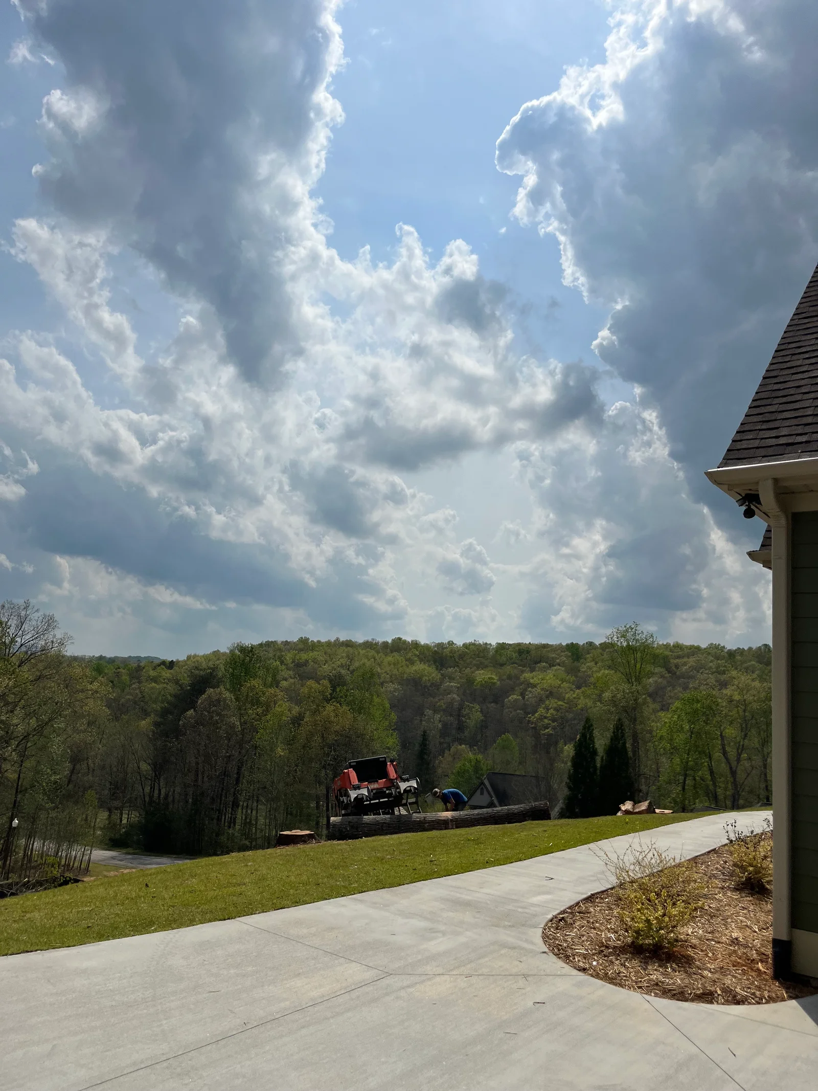 Tree removal equipment on hillside property with concrete patio and landscaped grounds